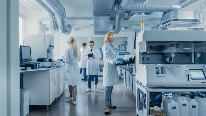 Scientists in lab coats using lab equipment in modern laboratory